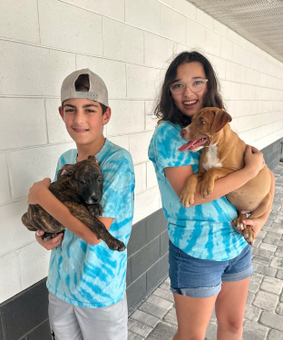Two youth volunteers holding puppies