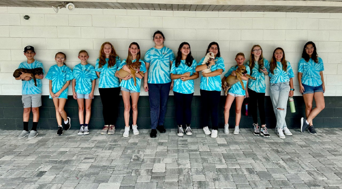 Line of youth volunteers by the building, some holding dogs