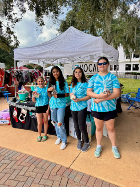 Four of the youth volunteers at a fundraising event in front of the VOCAL tent